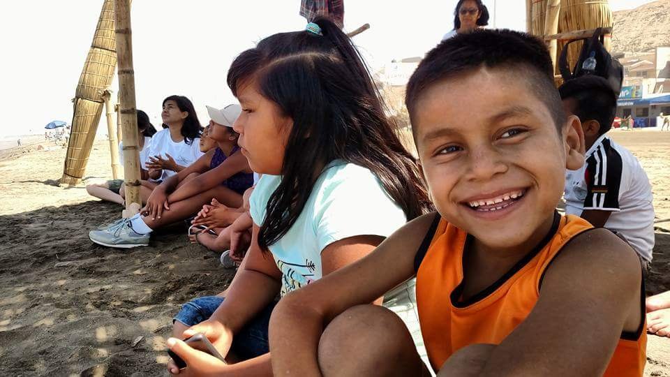 A smiling child sitting with a group near a beach