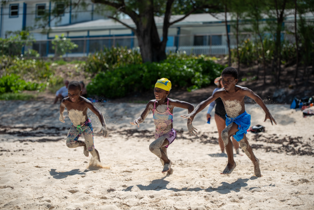 Children running together on a beach after a SwimTayka swimming session